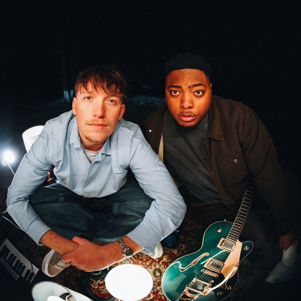 Sincer and Jude Barclay on a rug with a guitar